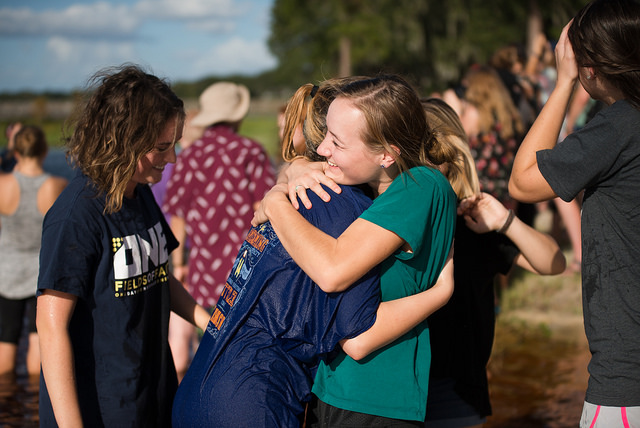 young women hugging in a crowd after baptism