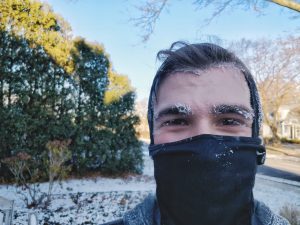 man running in cold with snow on his face